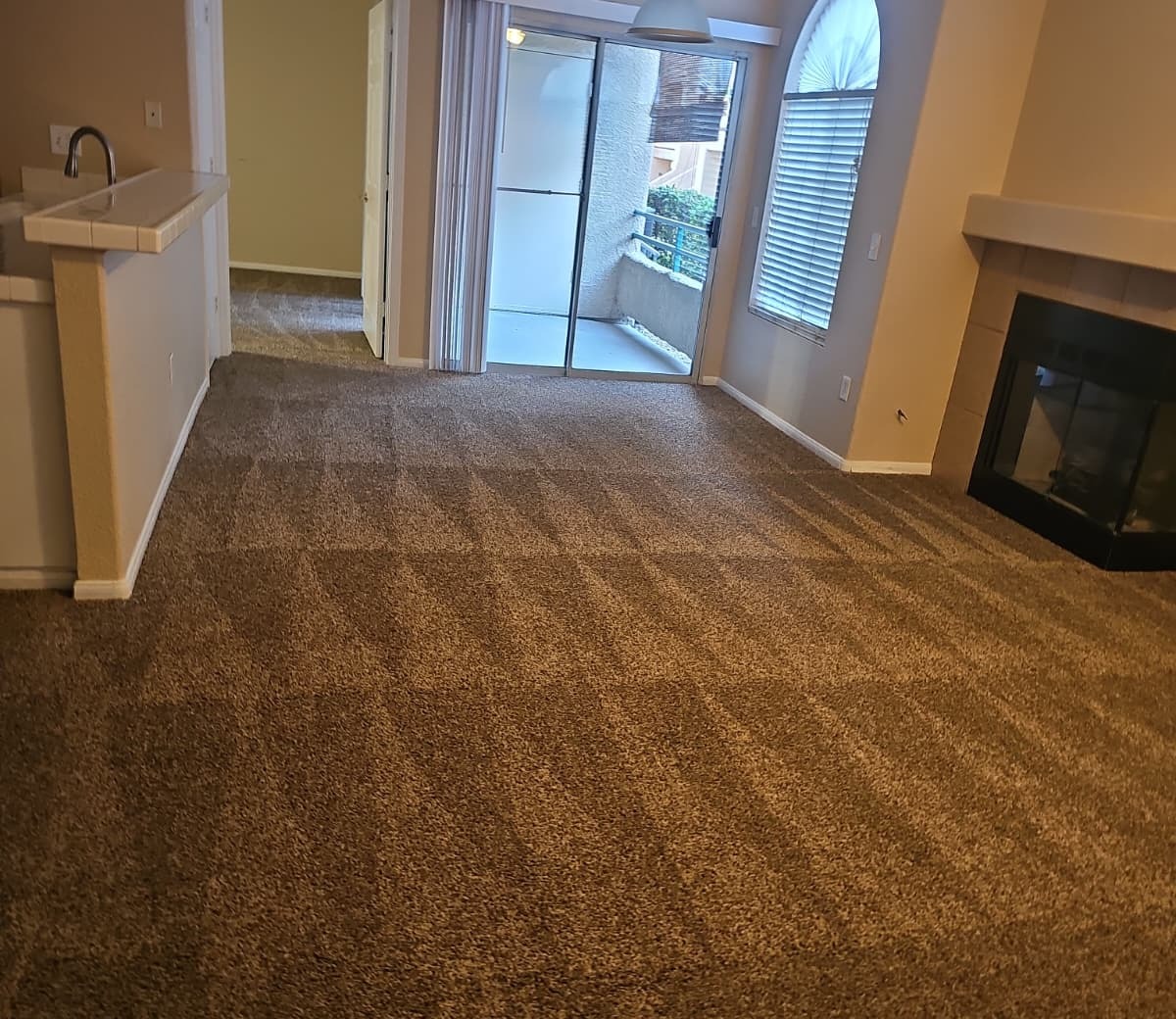 Freshly cleaned living room carpet near a fireplace