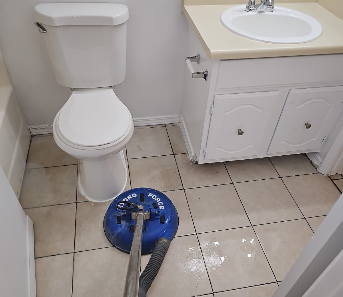Eagle Carpet Cleaners technician deep cleaning bathroom tile and grout with a rotary tool